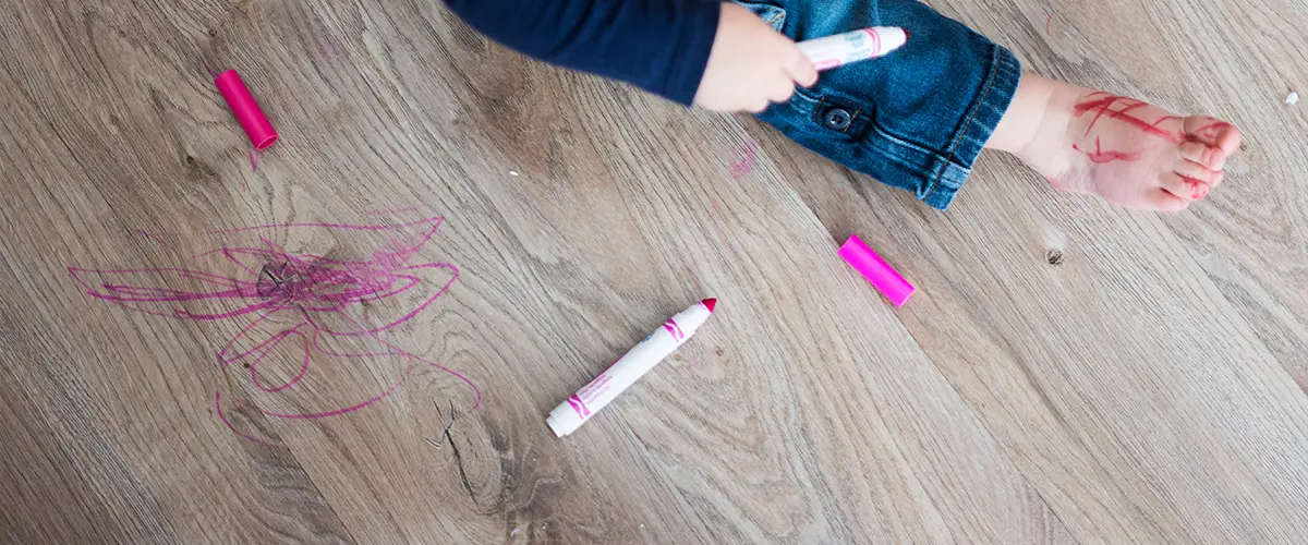 A kid drawing on a vinyl floor