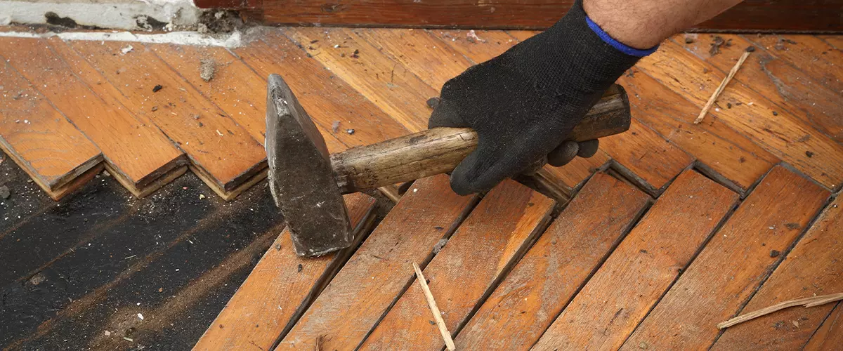 Worker removing old damaged parquet using hammer tool