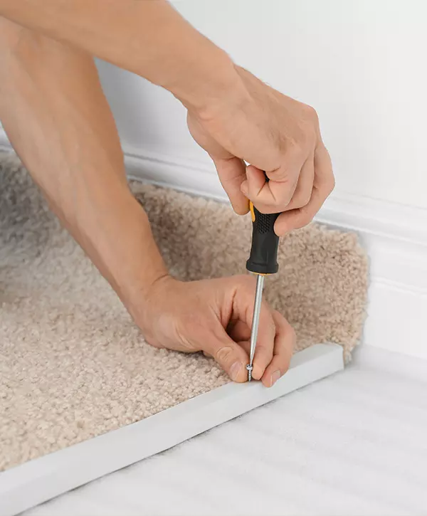 Carpet installation process in Oakdale California. Worker using screwdriver while installing new carpet flooring in room