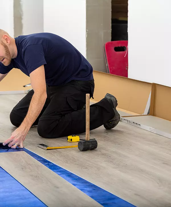 Worker joining click lock vinyl floor plank covering at home renovation. Man laying LVP flooring in Ceres, California